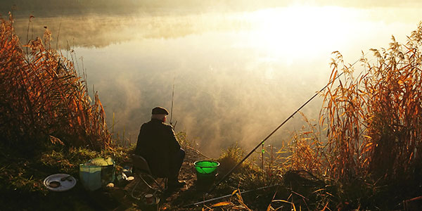 man fishing at sun rise at a lakeside