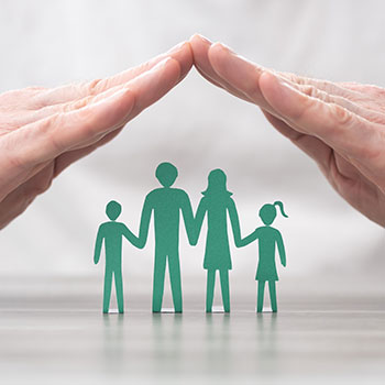 Hands forming protective arch over cutout paper family