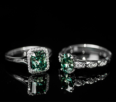 Two pieces of diamond jewellery with green stones set in ring clasp.